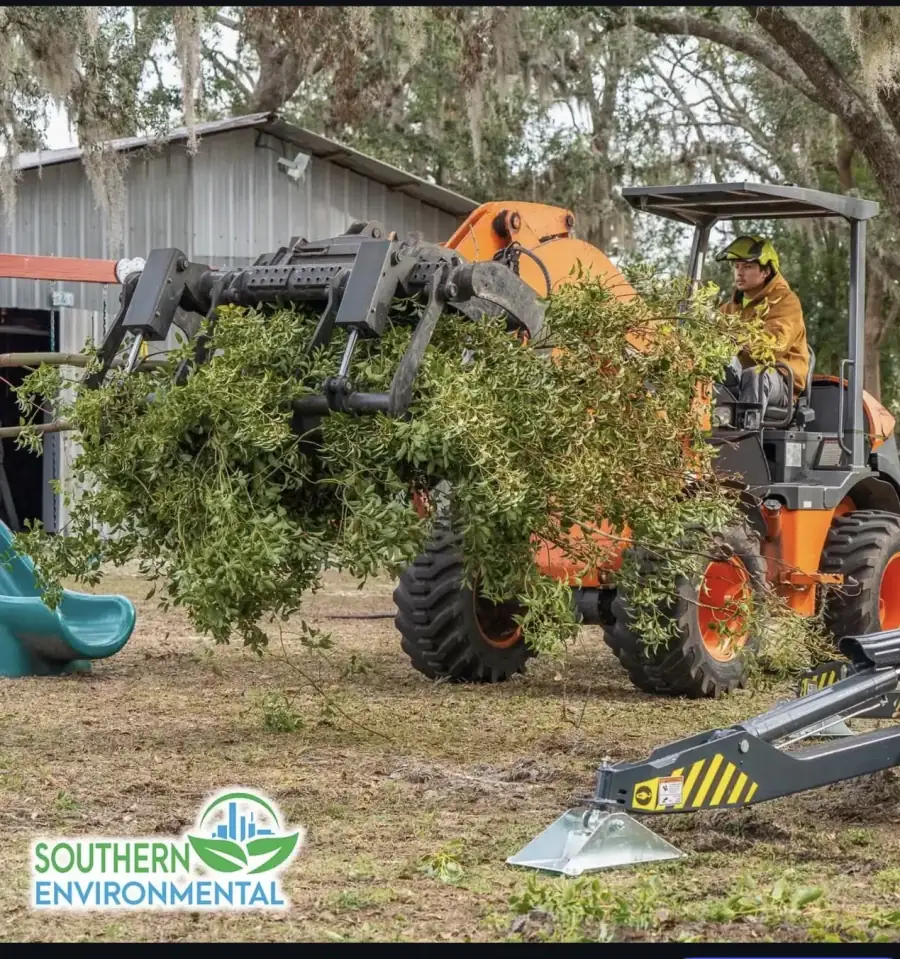 Southern Environmental Group compact articulated loader transporting cleared brush in Tampa Bay , specialized wheel loader with hydraulic grapple moving tree debris and brush at residential job site