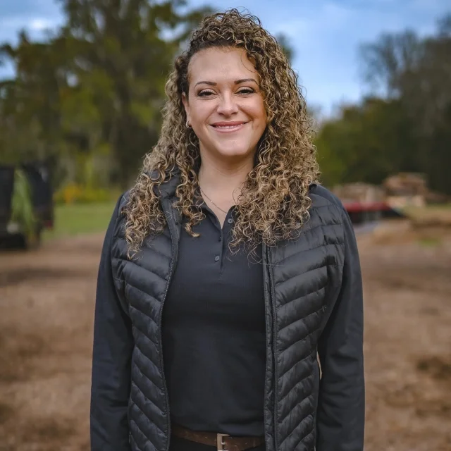 Candice Snyder smiling outdoors on a cleared job site, representing the dedicated team you meet when learning about Southern Environmental Group.