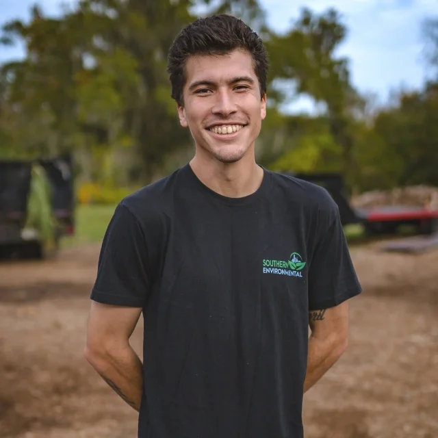 Damien Lopez smiling outdoors on a job site wearing a branded t-shirt, representing the friendly local professionals you will find when learning about Southern Environmental Group.