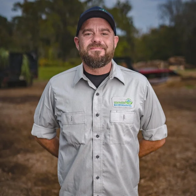 Daniel Nance of the Southern Environmental Group field crew, smiling in his branded uniform on a recently cleared job site, representing the team you will read about in the About Southern Environmental Group section.