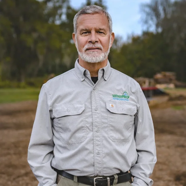 Jonathan Ernst wearing a branded work shirt on a land clearing job site, representing the experienced professionals you will find when learning about Southern Environmental Group.