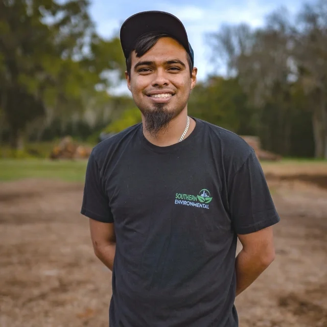 Justin Montana smiling on a land clearing site in his company uniform, representing the hard-working crew you see when reading about Southern Environmental Group.
