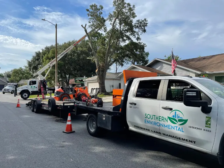 Southern Environmental service fleet with crane truck and equipment trailer staged for a residential emergency tree removal in a local neighborhood.