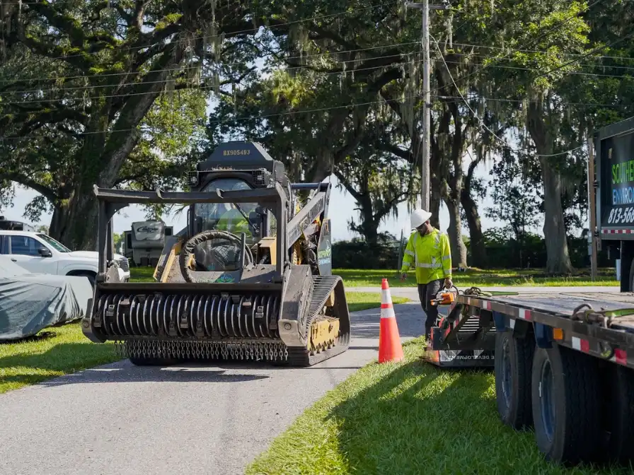 Southern Environmental operator using a specialized compact track loader for residential land clearing and brush removal on a private property.