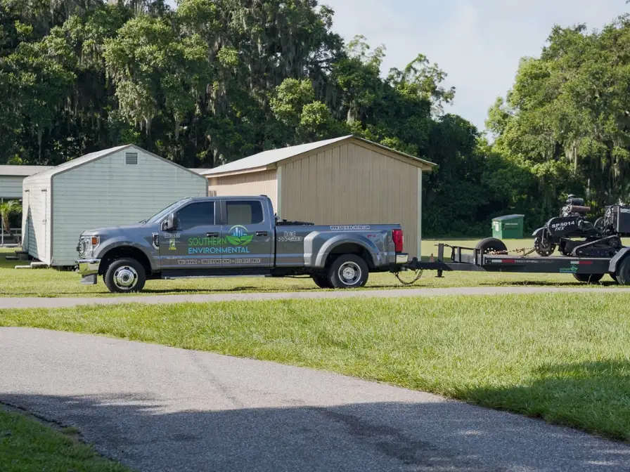 Southern Environmental service truck and trailer arriving at a residential property to perform professional pond cleaning and aquatic vegetation management.