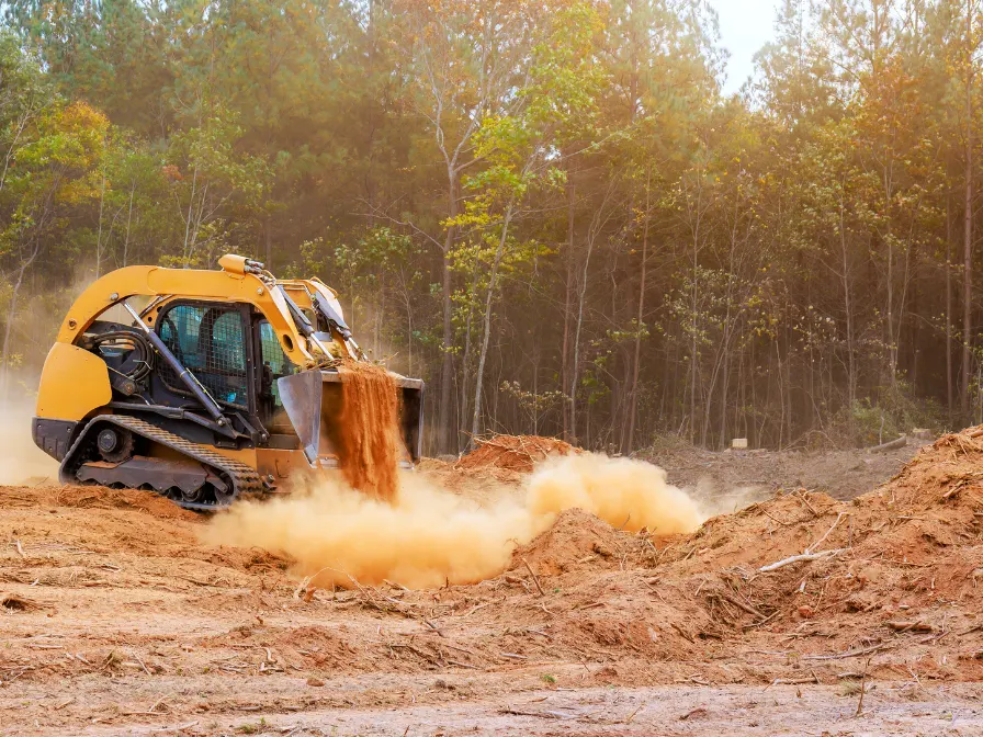 Yellow compact track loader performing site development and grading on a cleared land project for Southern Environmental.
