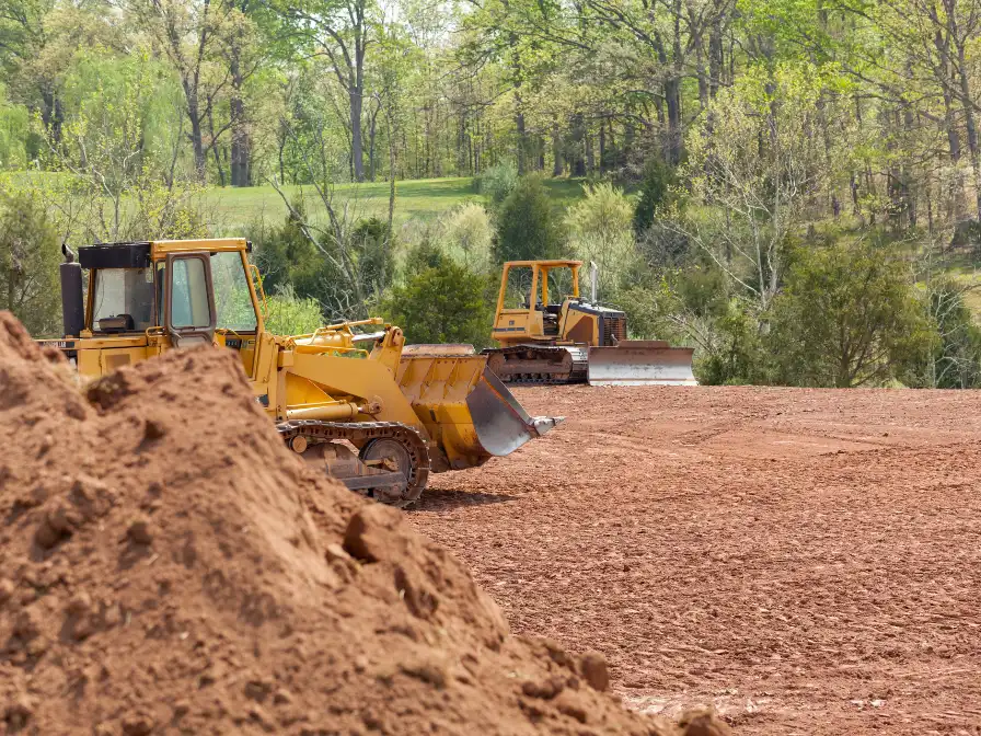 A bulldozer and track loader staged on a cleared lot, demonstrating the difference between land clearing and site excavation on a Florida property.
